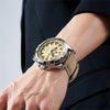 A close-up of a luxury men's quartz watch with a gold-toned dial and silver casing worn on a wrist against a dark suit sleeve