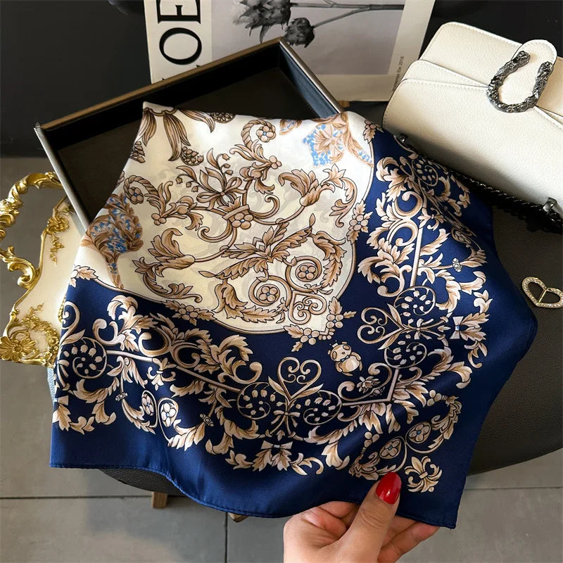 A deep blue silk scarf with intricate gold floral embroidery is displayed on a dark surface.