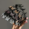 A black hair accessory featuring small, sparkling rhinestone butterflies arranged in a circular design.