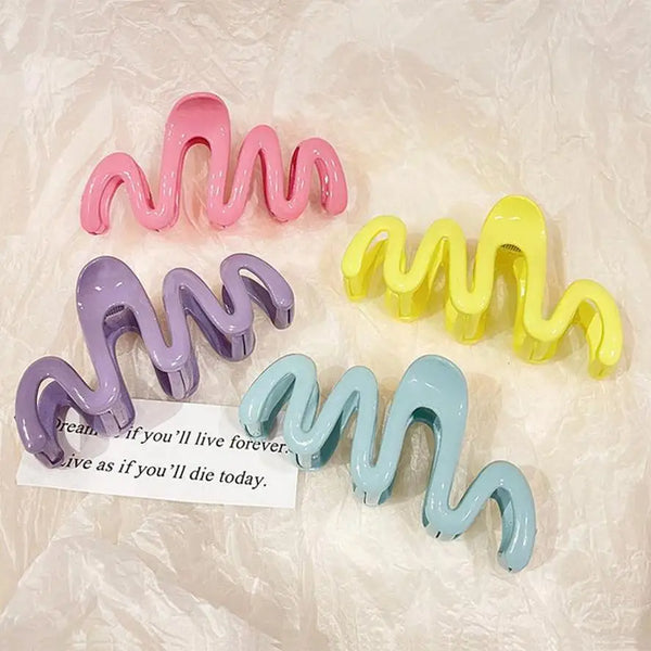 A collection of colorful jelly wave hair claw clips in pink, purple, and yellow are displayed on a white surface.