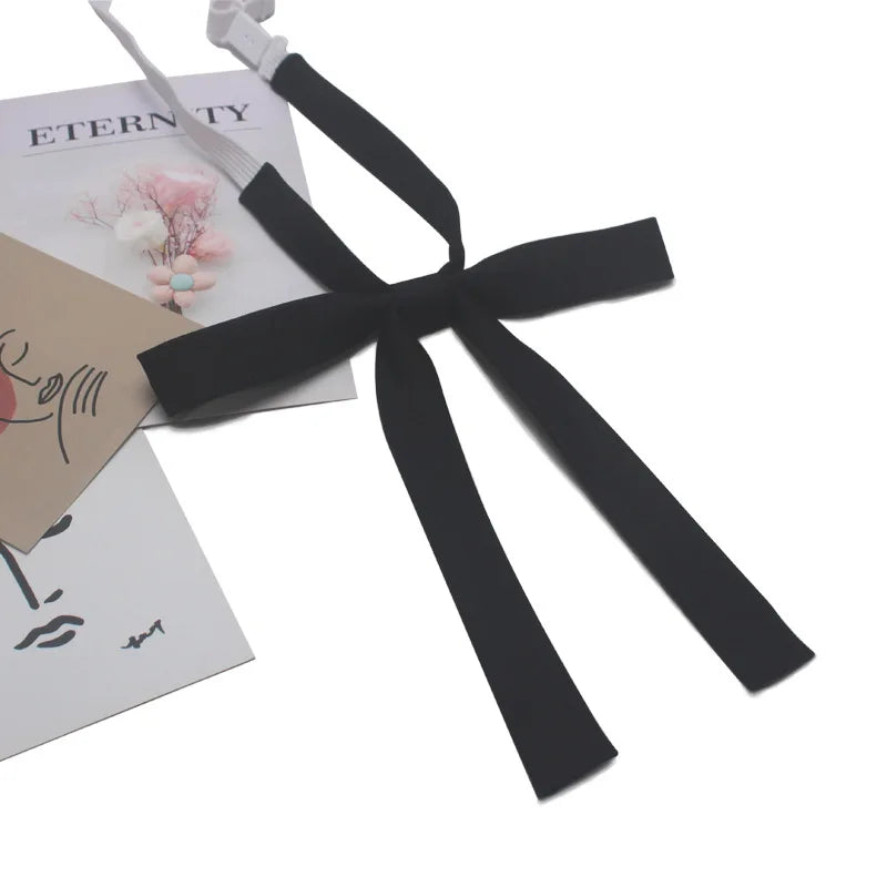 A black ribbon tie set with a butterfly knot is shown next to some paper and a pencil.
