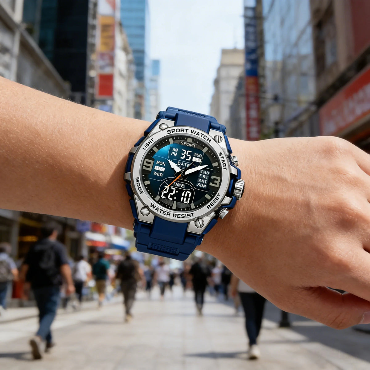 A close-up of a blue sports watch with a metal band worn on a person's wrist in an outdoor city setting.