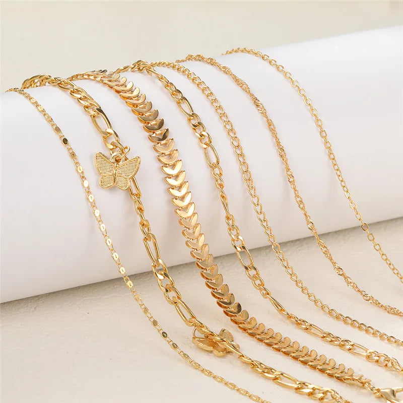 Ein Set goldener Vintage-Schmetterlings-Herz-Anklet, präsentiert auf einer weißen Oberfläche.
