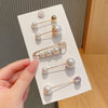 A hand holds a display of pearl brooch pins for customizing apparel, showing various sizes and styles.