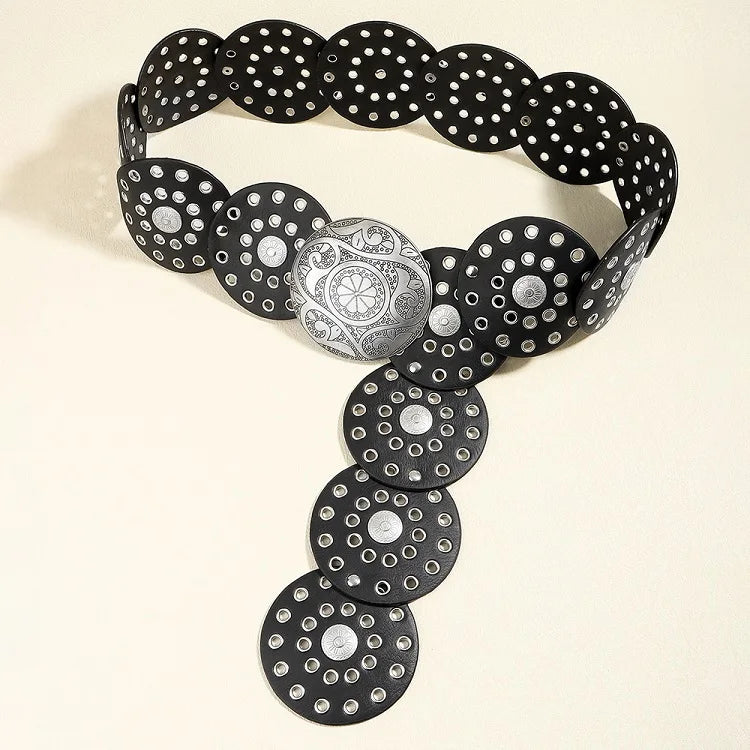 A black denim belt featuring various circular studs and a decorative silver medallion.