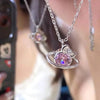 A close-up of a pink heart zircon clavicle necklace with a silver chain and pendant worn by a person.