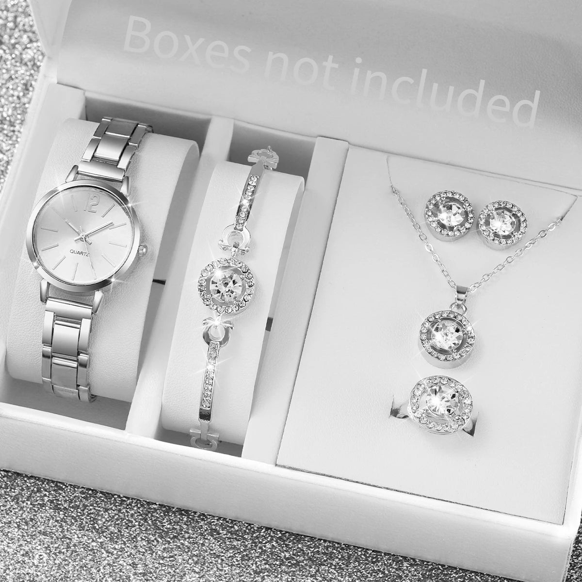 A white box contains an elegant quartz wrist watch, a diamond pendant necklace, and a ring set.