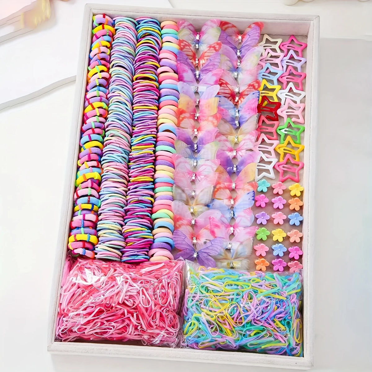 A box filled with colorful decorative hair accessories including scrunchies and ties in various shades of pink, purple, blue,