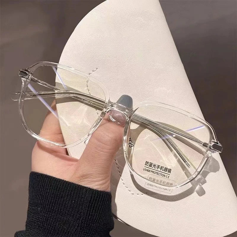 A hand holds a pair of clear wire-frame glasses with purple accents against a white background.