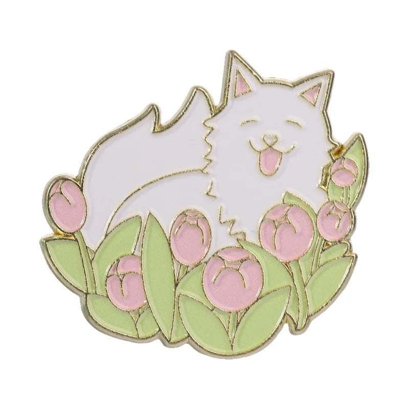 A gold-edged enamel brooch featuring a white cat and pink flowers on a green background.