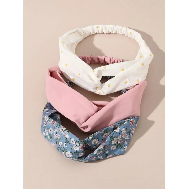 Ein Set von vier weichen Stoff-Haarbändern mit floralen Mustern in Weiß und Pink.
