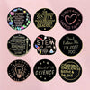 A collection of black lapel pins featuring inspirational quotes and symbols like a heart, a lightbulb, and text related to fa
