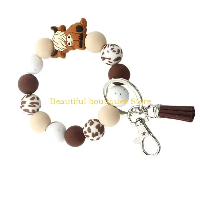 A keychain featuring a series of brown and white spotted silicone beads shaped like a Highland cow face.