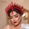 A woman wearing a red rhinestone bridal crown headband with gold accents and long earrings.