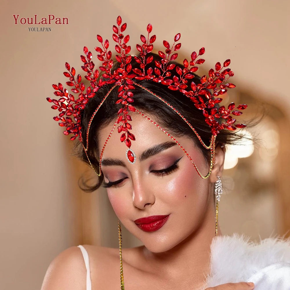 A woman wearing a red rhinestone bridal crown headband with gold accents and long earrings.