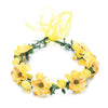 A yellow floral wreath headband made of flowers and green leaves with a sheer yellow ribbon.