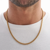A close-up of a gold Cuban link chain necklace worn around the neck against a white shirt.