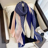Luxuriöses Baumwoll-Pashmina-Schal in Blau-, Pink- und Cremetönen, drapiert auf einem hellen Sofa.
