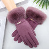 A close-up of a pair of plush, mauve wrist gloves with fluffy faux fur cuffs resting on a white surface.