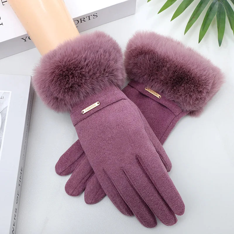 A close-up of a pair of plush, mauve wrist gloves with fluffy faux fur cuffs resting on a white surface.