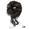 A close-up of messy black synthetic hair styled into a loose bun or ponytail.