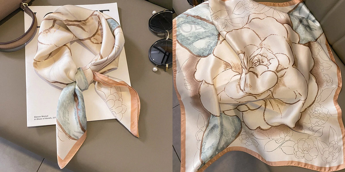 A light beige silk scarf with a floral print featuring soft peach and muted blue tones.