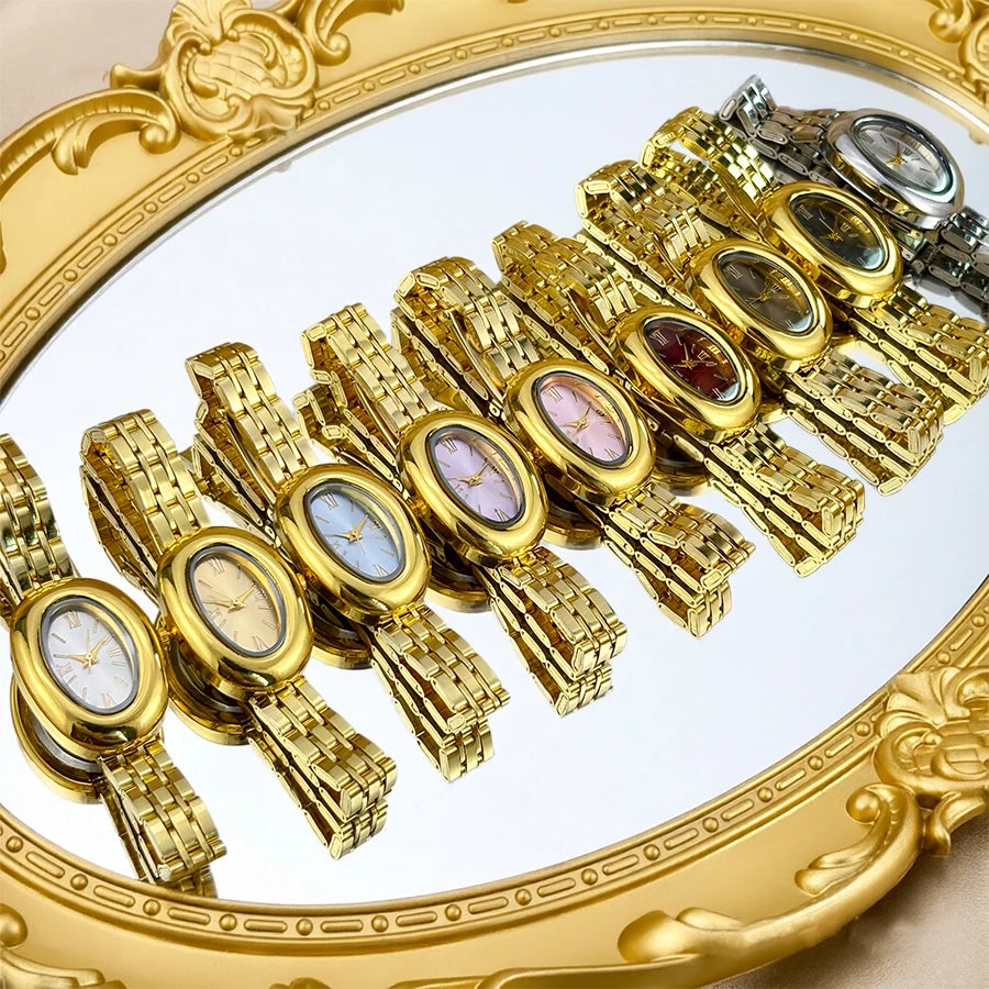 Una fila de relojes vintage con cajas doradas y correas de acero, exhibidos en un marco dorado ornamentado.