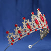 A gold crystal rhinestone tiara and headband set with red gemstones against a blue background.