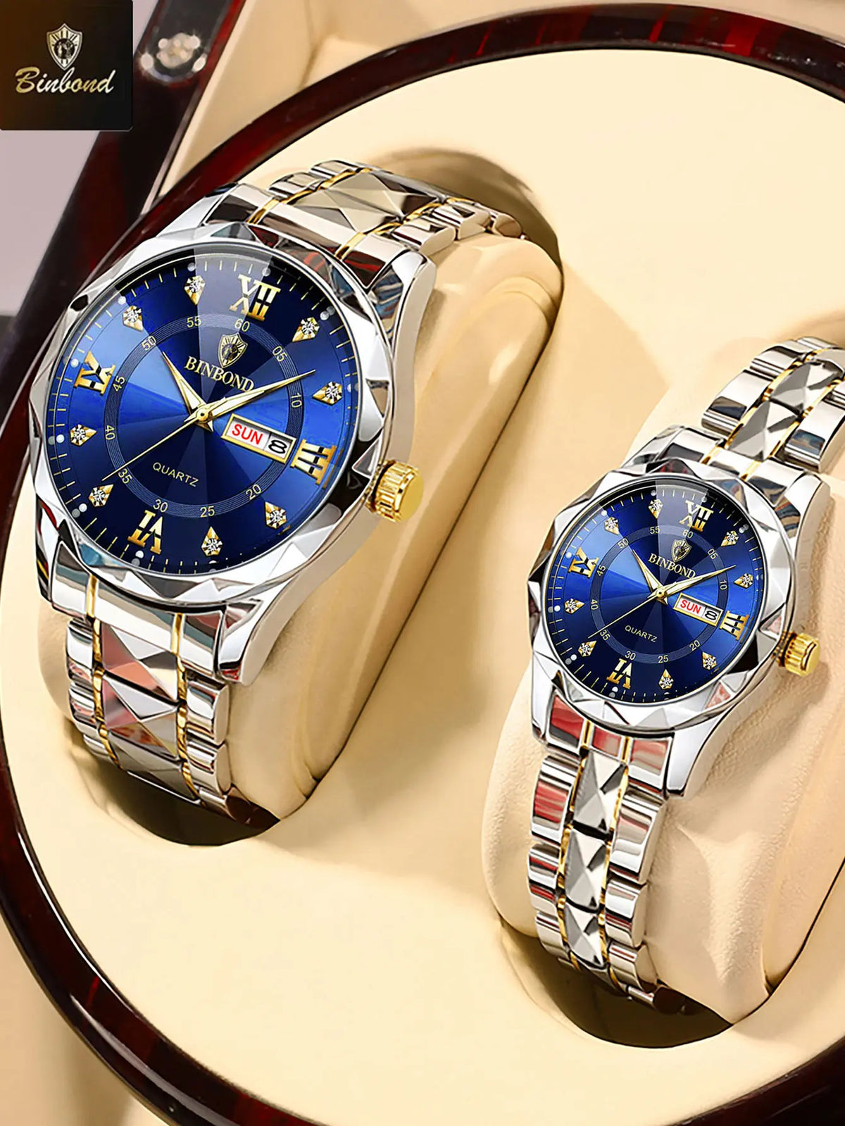 A pair of shiny stainless steel couple watches with blue dials and gold accents displayed on a light-colored surface.