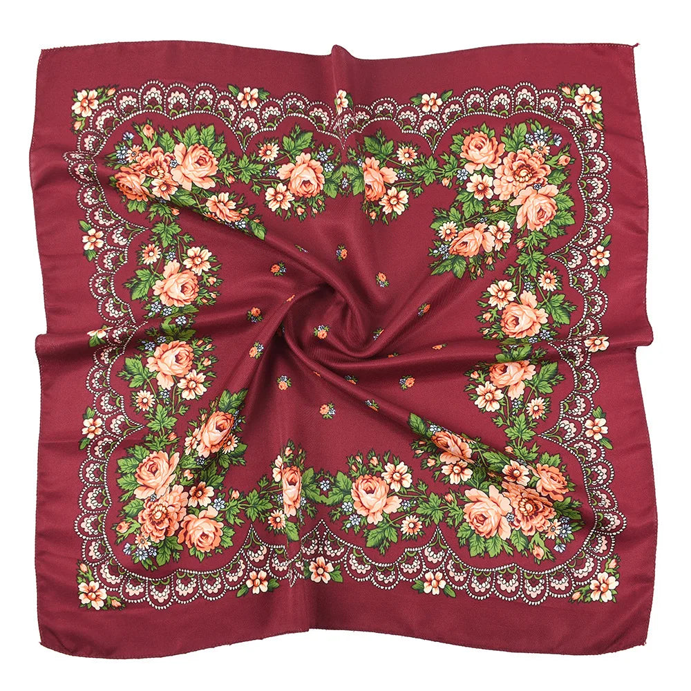 A deep red silk scarf featuring a detailed floral print with roses and greenery.