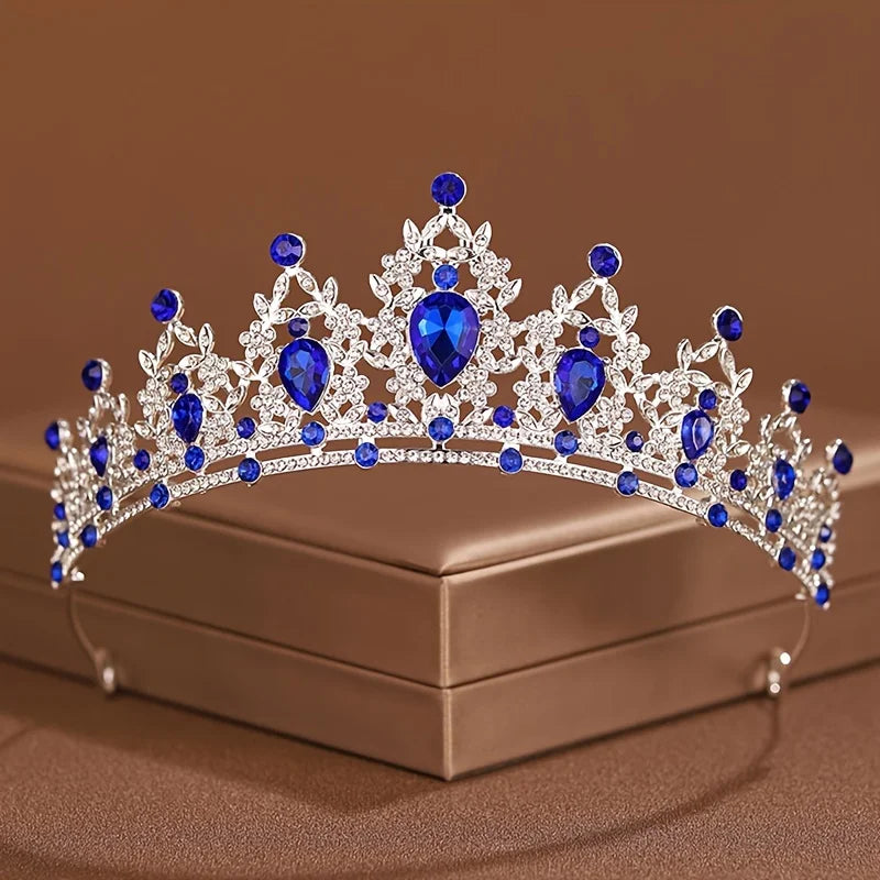Diadema de cristal plateado y azul con intrincados diseños barrocos, mostrada en una caja.
