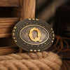 A vintage western belt buckle with an ornate gold design resting on a wooden surface.