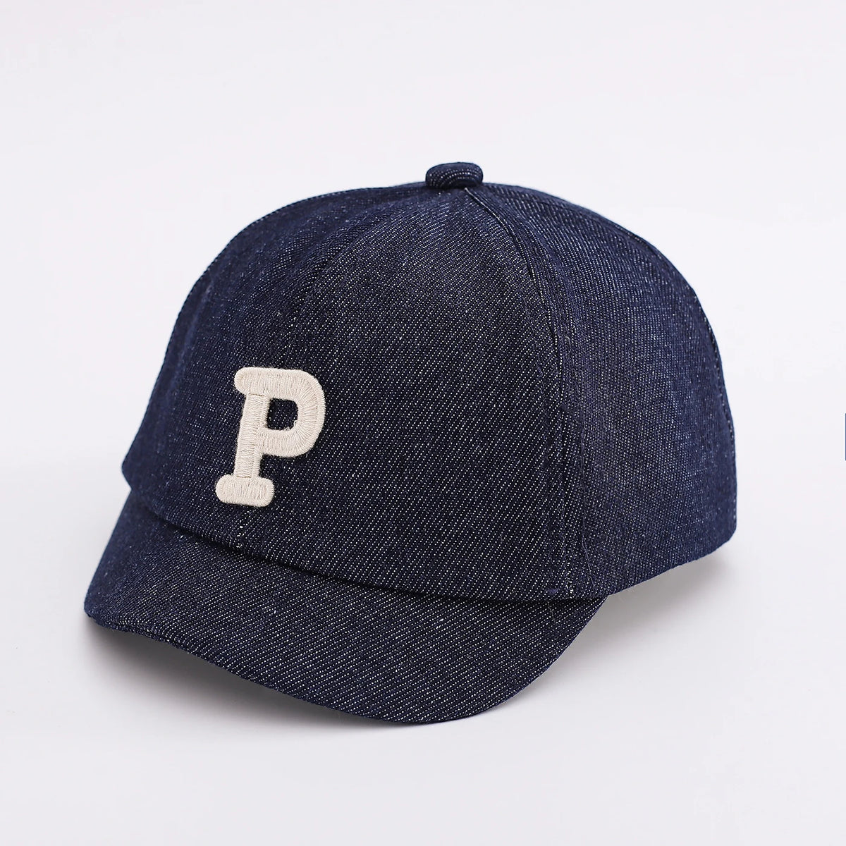 A dark navy denim baseball cap with a light beige letter P embroidered on the front.