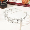 Clear acetate toothed headbands displayed on a white surface next to a book and a cactus bottle.