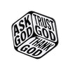 Broche émail géométrique noir et blanc en forme de cube avec les mots ASK GOD TRUST GOD THANK GOD gravés sur ses faces.