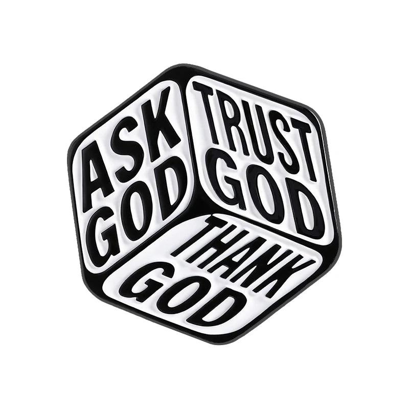 Broche émail géométrique noir et blanc en forme de cube avec les mots ASK GOD TRUST GOD THANK GOD gravés sur ses faces.