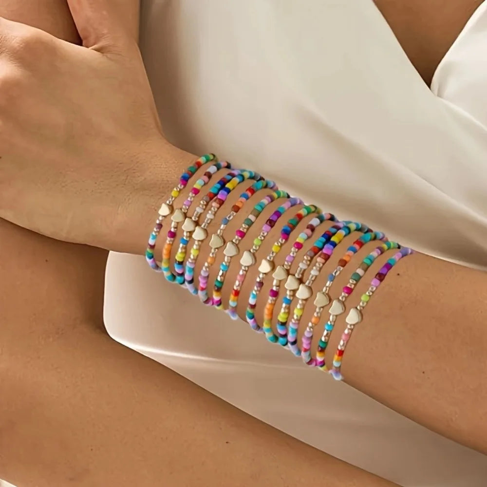 A close-up of a hand wearing a stack of colorful resin beaded bracelets on the wrist.