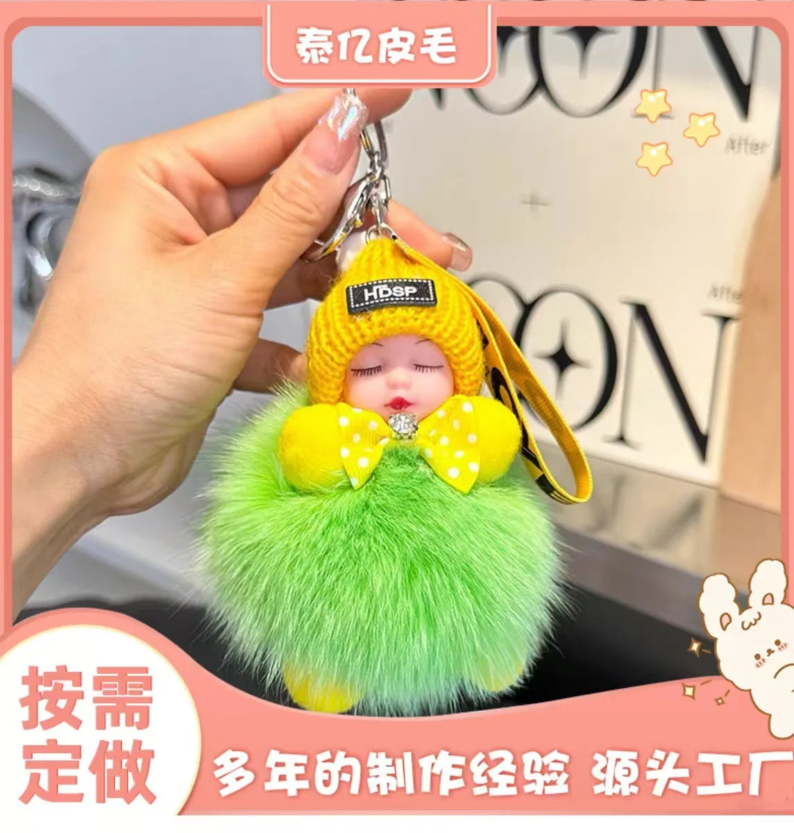 A hand holds a bright green fluffy plush doll with yellow accents and a knitted hood, resembling a cartoon character keychain