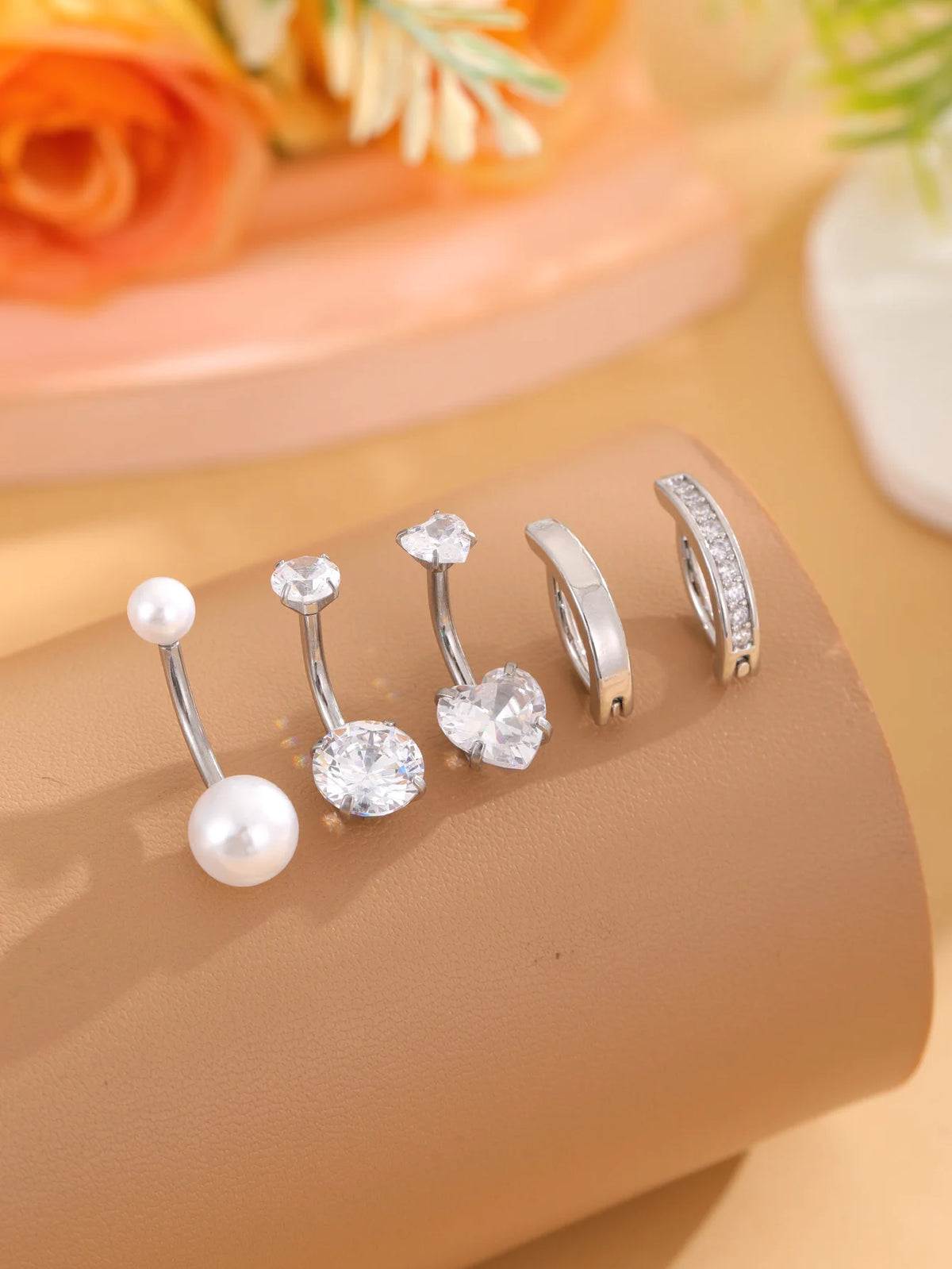 A set of five gold stainless steel dangled belly button rings displayed on a neutral background.
