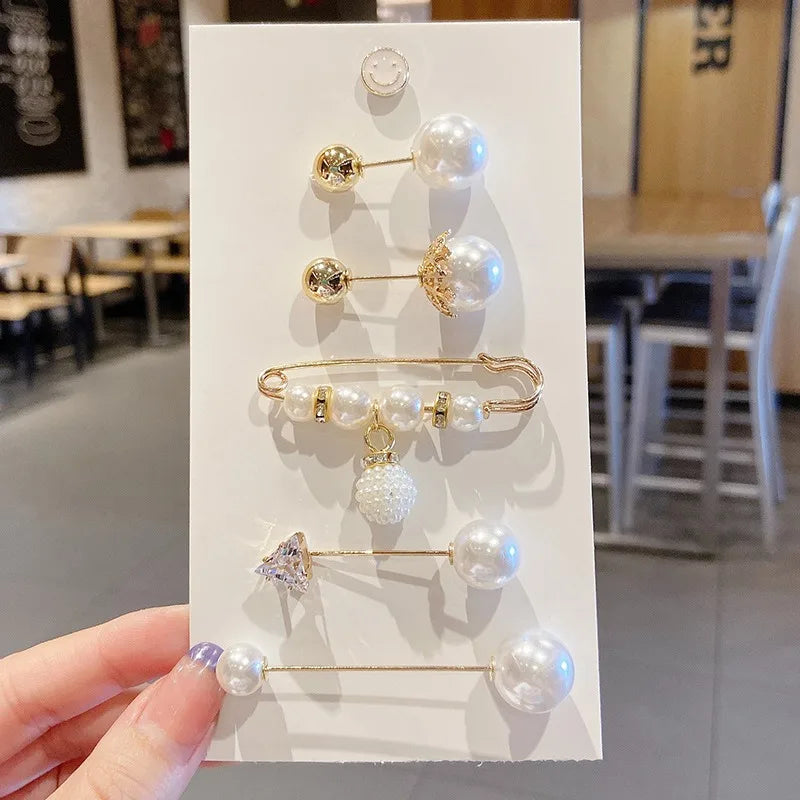 Una mano sostiene una exhibición de elegantes alfileres para prendedores de perlas, con varios tamaños y estilos.