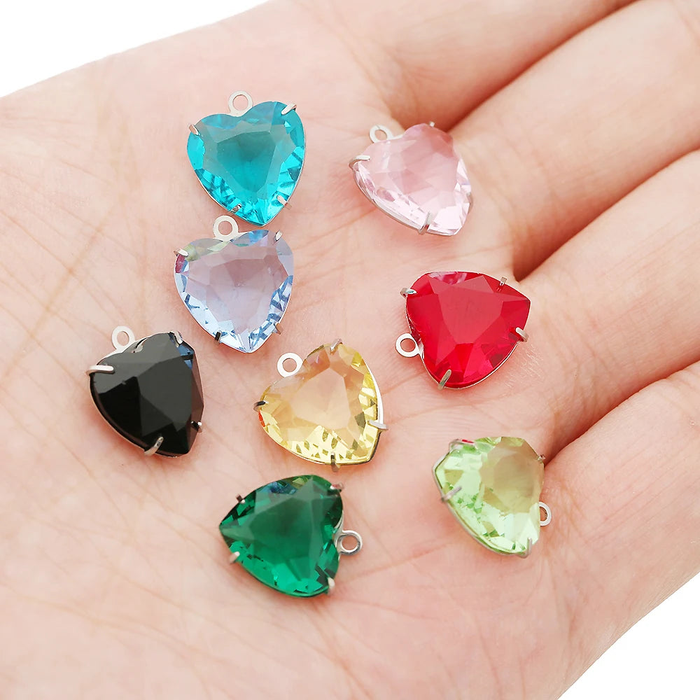 Five heart-shaped crystal pendants in various shades of blue, pink, red, and green displayed on a hand.