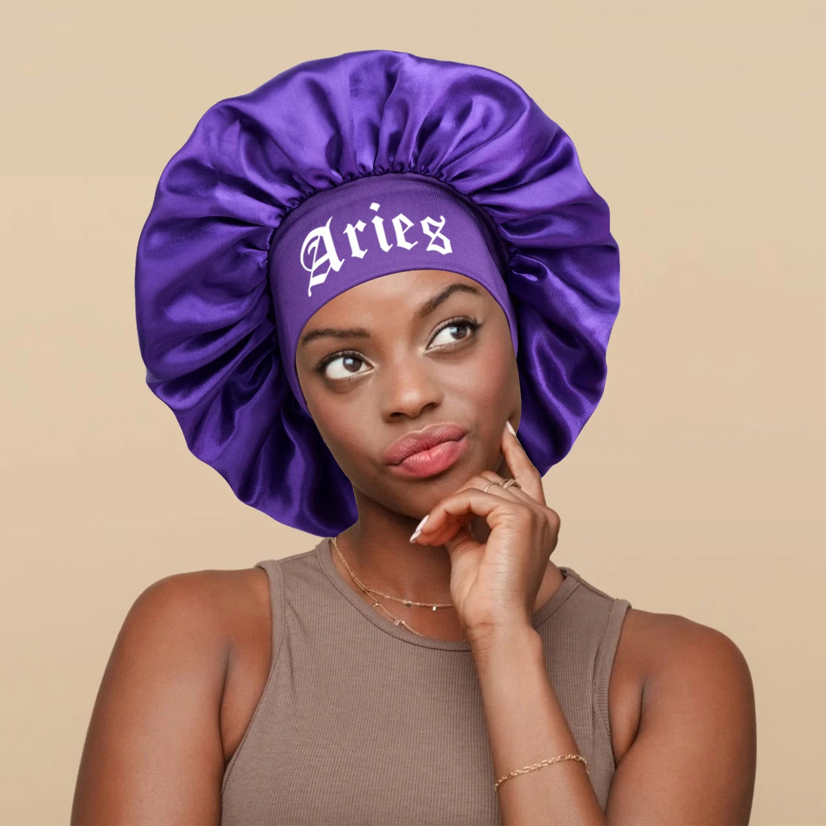 A woman wearing a purple satin sleep bonnet with an Aries wrap band.
