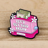 A pink enamel pin featuring the text Let's Get This Bread and a stack of dollar bills.
