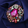 Broche florale en cristal élégante avec des gemmes roses et vertes dans un métal doré.
