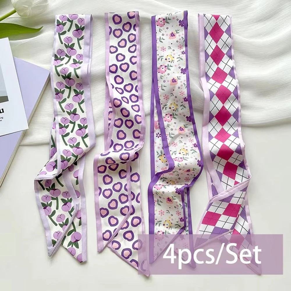 A set of four silk satin hair and bag accessories featuring purple and pink patterned ribbons.