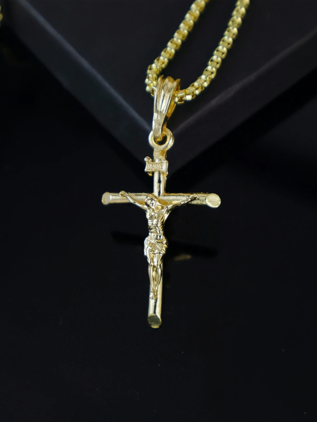 Goldplattiges Jesus-Kreuz-Anhänger mit Kette, präsentiert vor dunklem Hintergrund.
