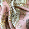 A close-up of a pink silk print shawl featuring intricate gold and brown chain and vine patterns.