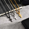A collection of gold and silver stainless steel Cuban link necklaces with cross pendants displayed on a light surface.