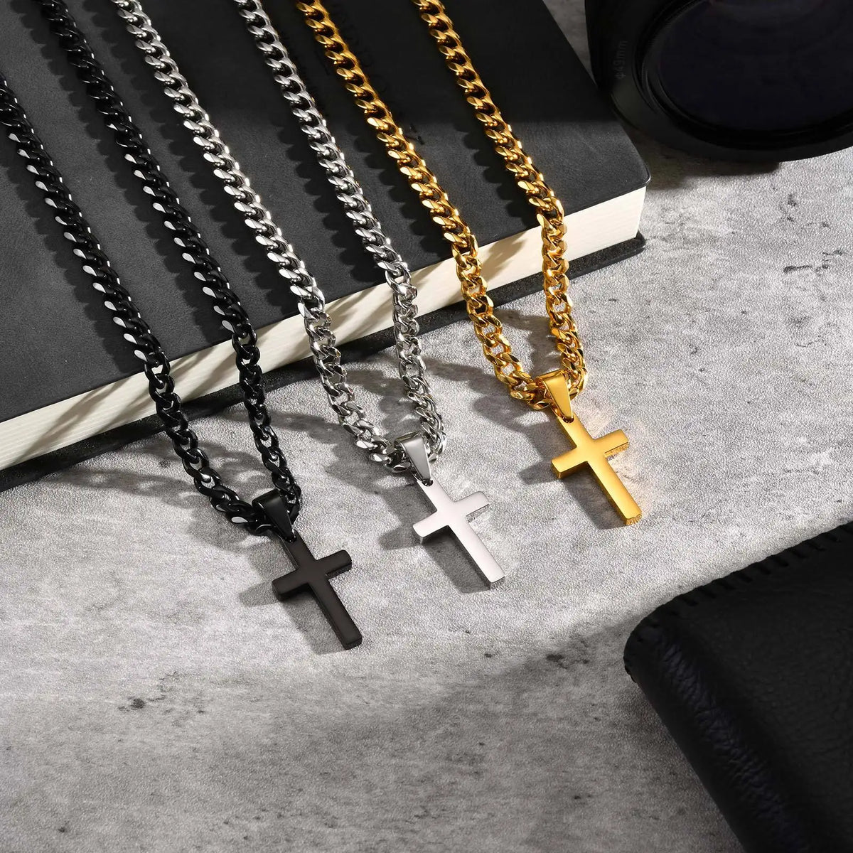 A collection of gold and silver stainless steel Cuban link necklaces with cross pendants displayed on a light surface.