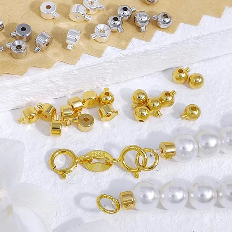 A collection of gold-colored jewelry findings including split rings, jump rings, and bead stoppers displayed on white fabric.